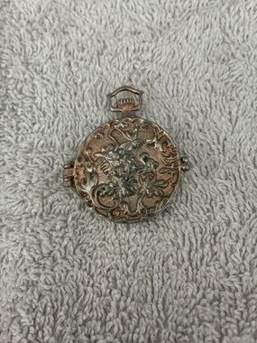 Vintage pocket watch style, featuring a decorative mermaid motif on inside cover